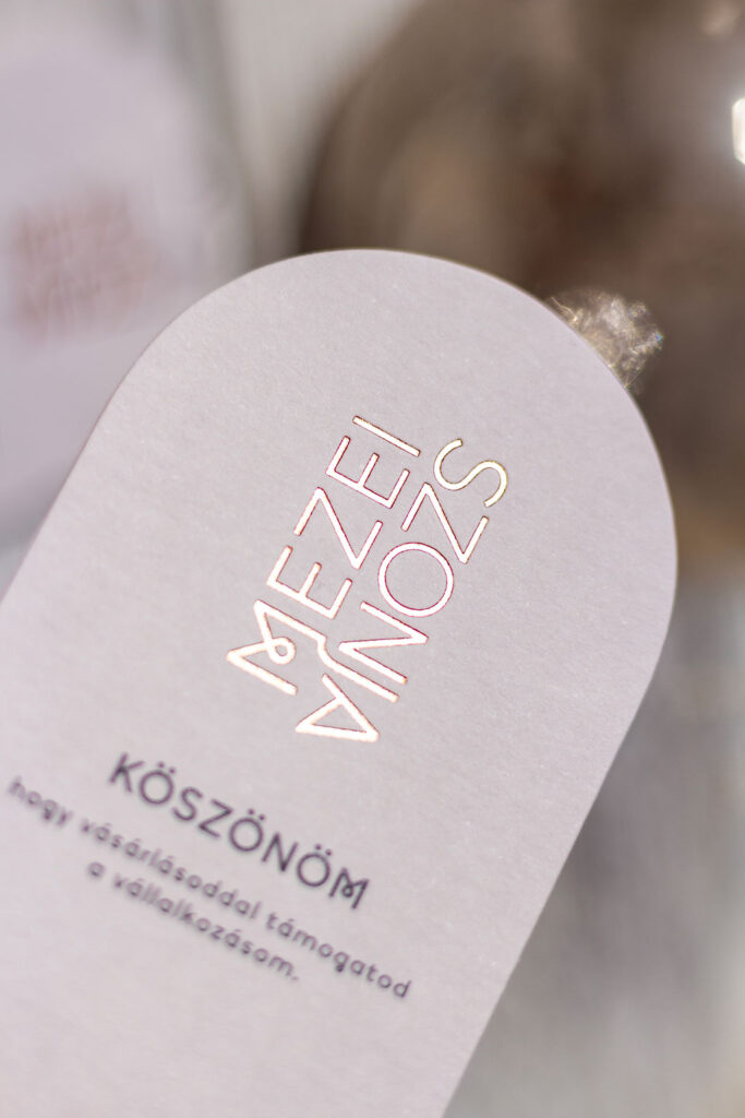 Boltíves névjegykáryta rosegold prégeléssel anyagában színezett, halvány púder papíron, köszönetkártyával és ruhacímkével kiegészítve