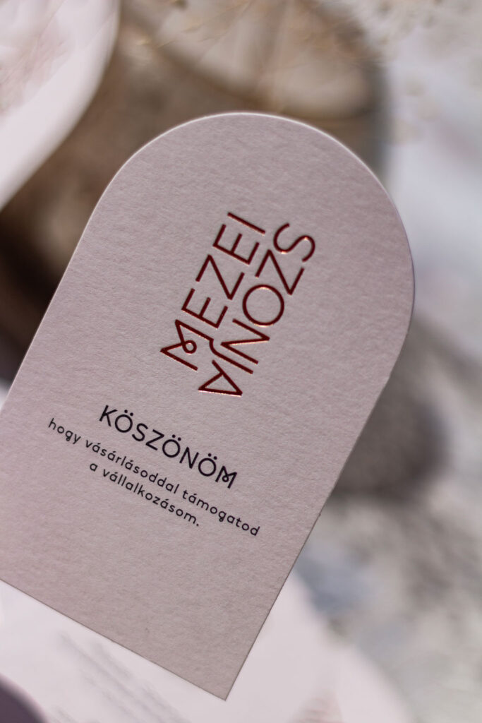 Boltíves névjegykáryta rosegold prégeléssel anyagában színezett, halvány púder papíron, köszönetkártyával és ruhacímkével kiegészítve